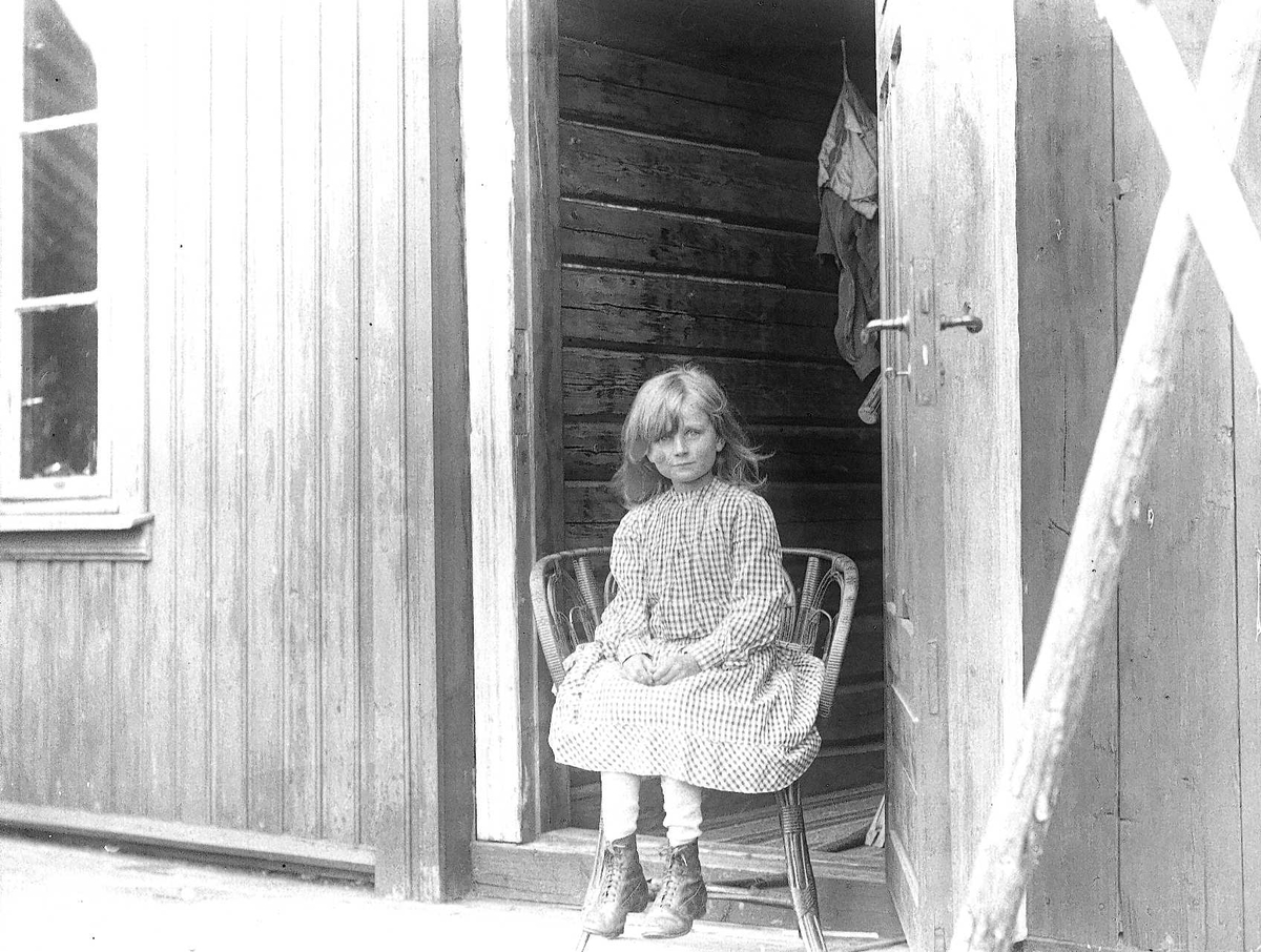 Axel Quinsgaard Wiborg, Holoa seter, Hadeland, Jevnaker, Oppland 1903. Gudrun Q. Wiborg sitter på stol i døråpning.