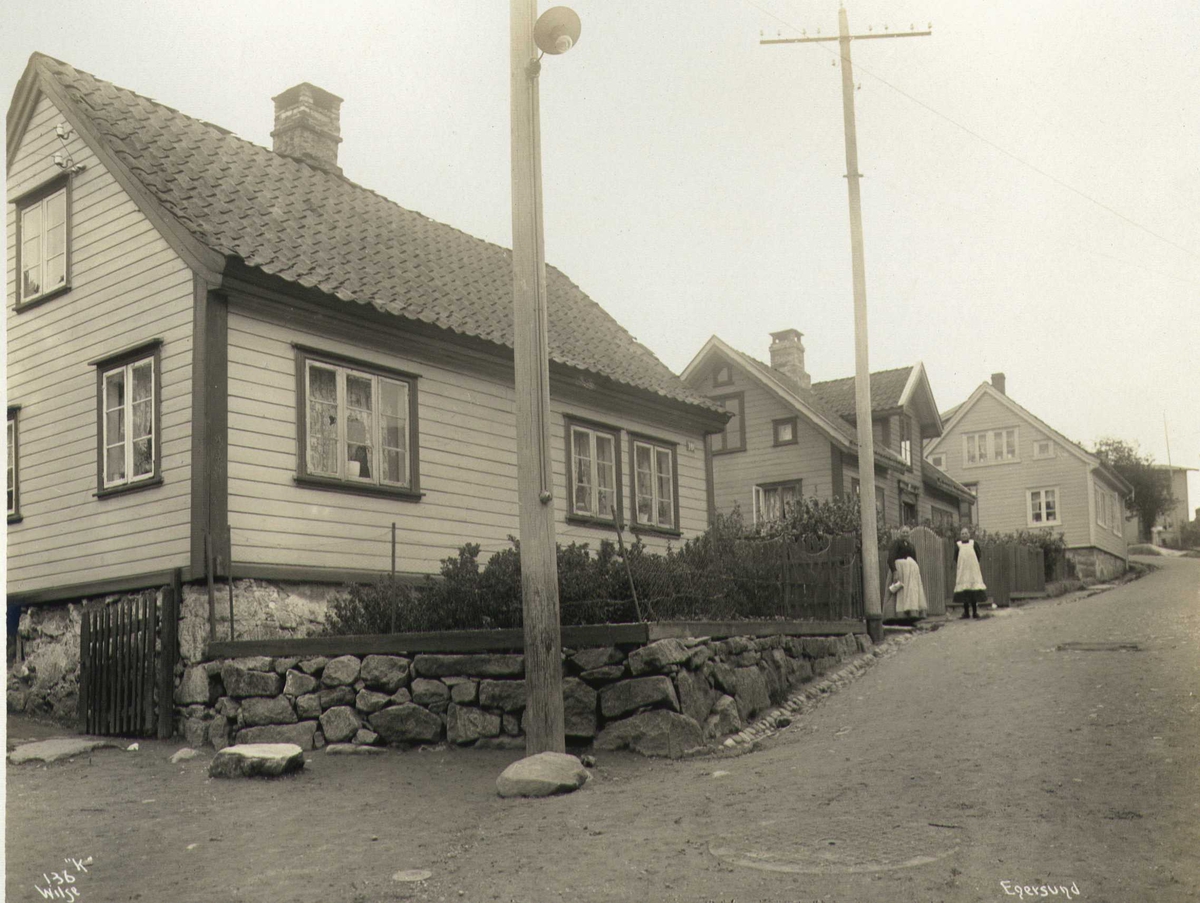 Anders Beer Wilse, Gateparti, Egersund, Eigersund, Rogaland. Eldre kvinne og jente utenfor et gjerde. Fotografert 1912.