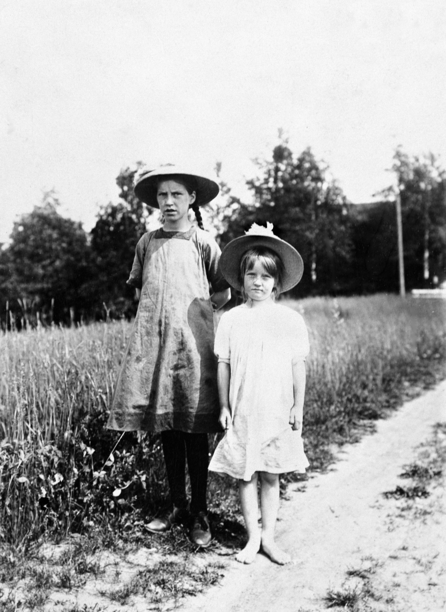 Anno Domkirkeodden, To jenter med kjoler og hatter. Oddlaug Trønnes og Solveig Trønnes.