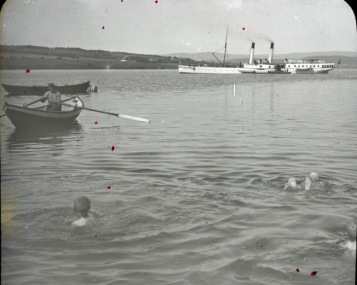 Anno Domkirkeodden, Bilder fra dagliglivet på Toftes Gave, Helgøya. Gutter fra som bader i Mjøsa. Passes på av mann i robåt. Mjøsbåten i Nessundet er D.S. Kong Oscar.