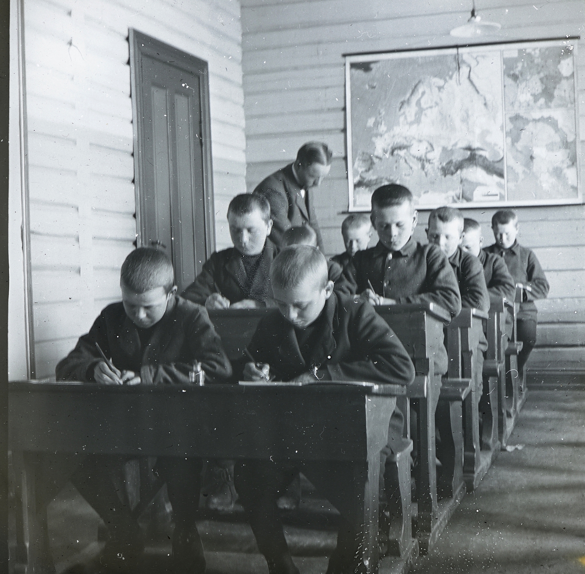 Anno Domkirkeodden, Bilder fra dagliglivet på Toftes Gave, Nedre Sund, Helgøya. Interiør fra skolesalen. Gutter ved pulter og lærer som instruerer.