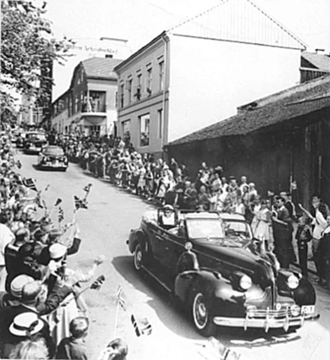Anno Domkirkeodden, HKH. KONG OLAV V, PRINSESSE ASTRID I ÅPEN BIL C-1, BUICK 1939, SIGNINGSFERDEN, MYE FOLK HILSER DE KONGELIGE MED NORSKE FLAGG, SEMINARGATA, BILEN BAK ER EN FORD ZEPHYR 1952-56