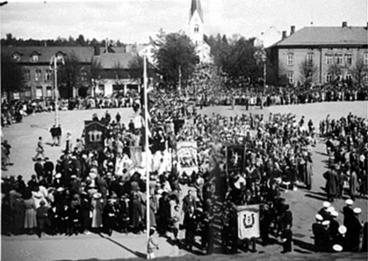 Anno Domkirkeodden, STORTORGET, 17 MAI. MYE FOLK, MUSIKKORPS OG FANER, SETT FRA BASARBYGNINGEN.