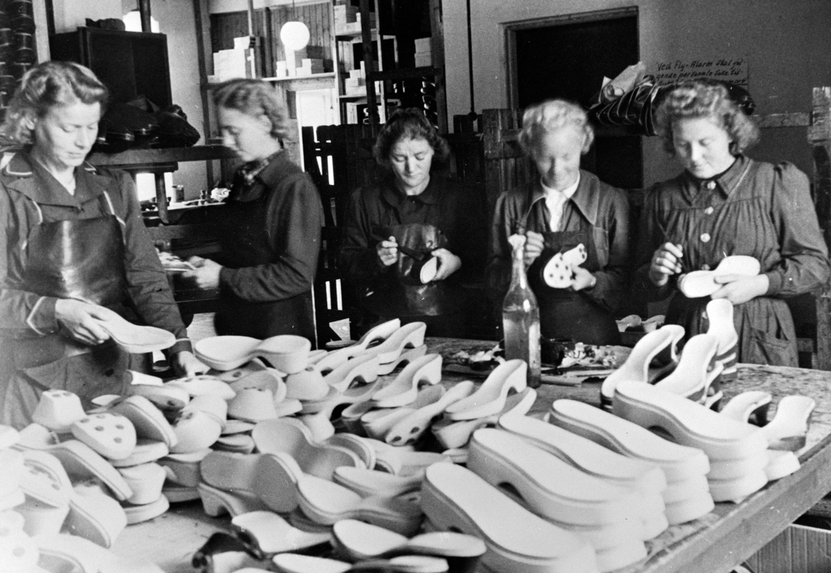 Anno Domkirkeodden, Skoproduksjon, Nørrøna skofabrikk, Falsensgate 12, Hamar. 1941. Mangel på materiale gjorde at bunningen, sålene, måtte lages i tre. Fra venstre Jenny Emilsen, Gerd Jensen, Karen Mikkelsen, Mary Kubberud, og Astrid Larsen pensler bunning. (såler)