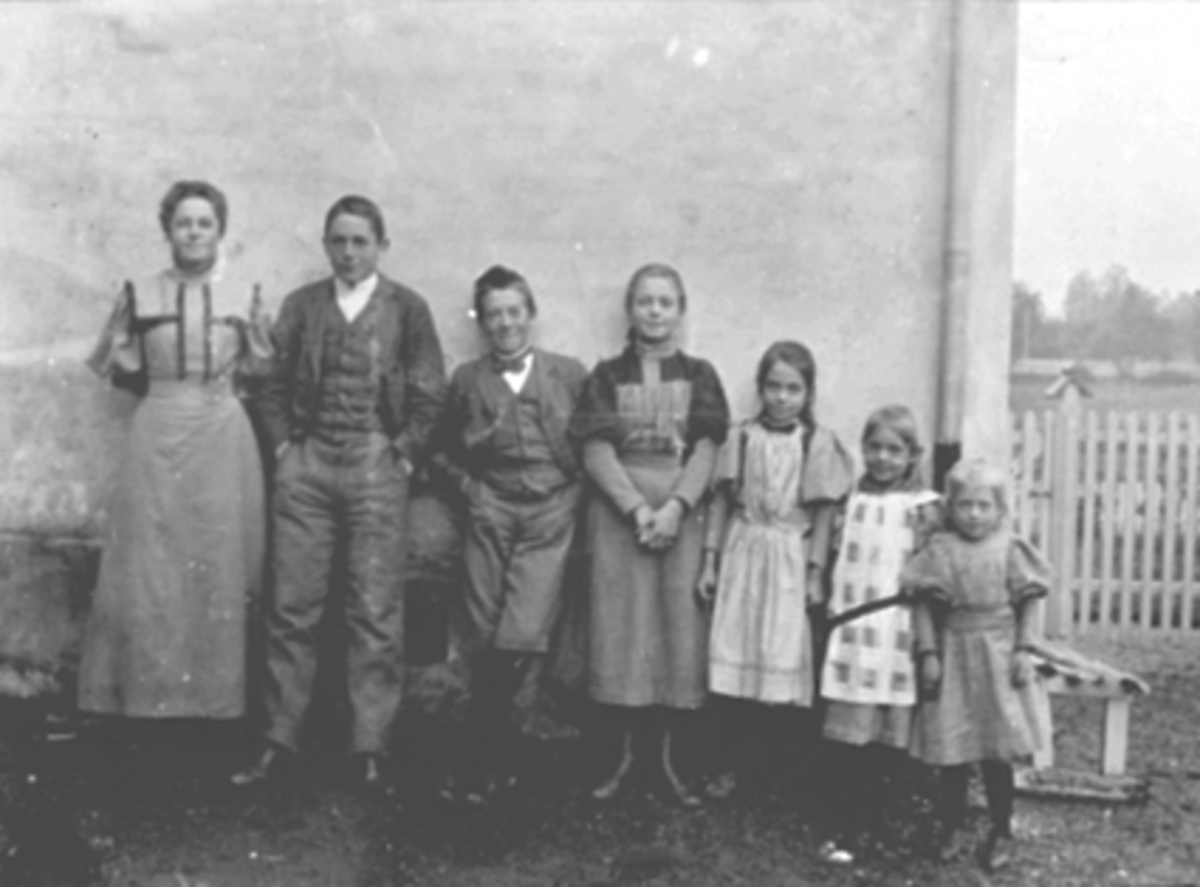 Anno Domkirkeodden, GRUPPE 7 BARN OG UNGDOM VED HUSVEGG, FRA VENSTRE INGEBORG, RAGNAR, SIGURD, ASTRID, KAREN, KRISTINE, TORDIS PETERSEN
