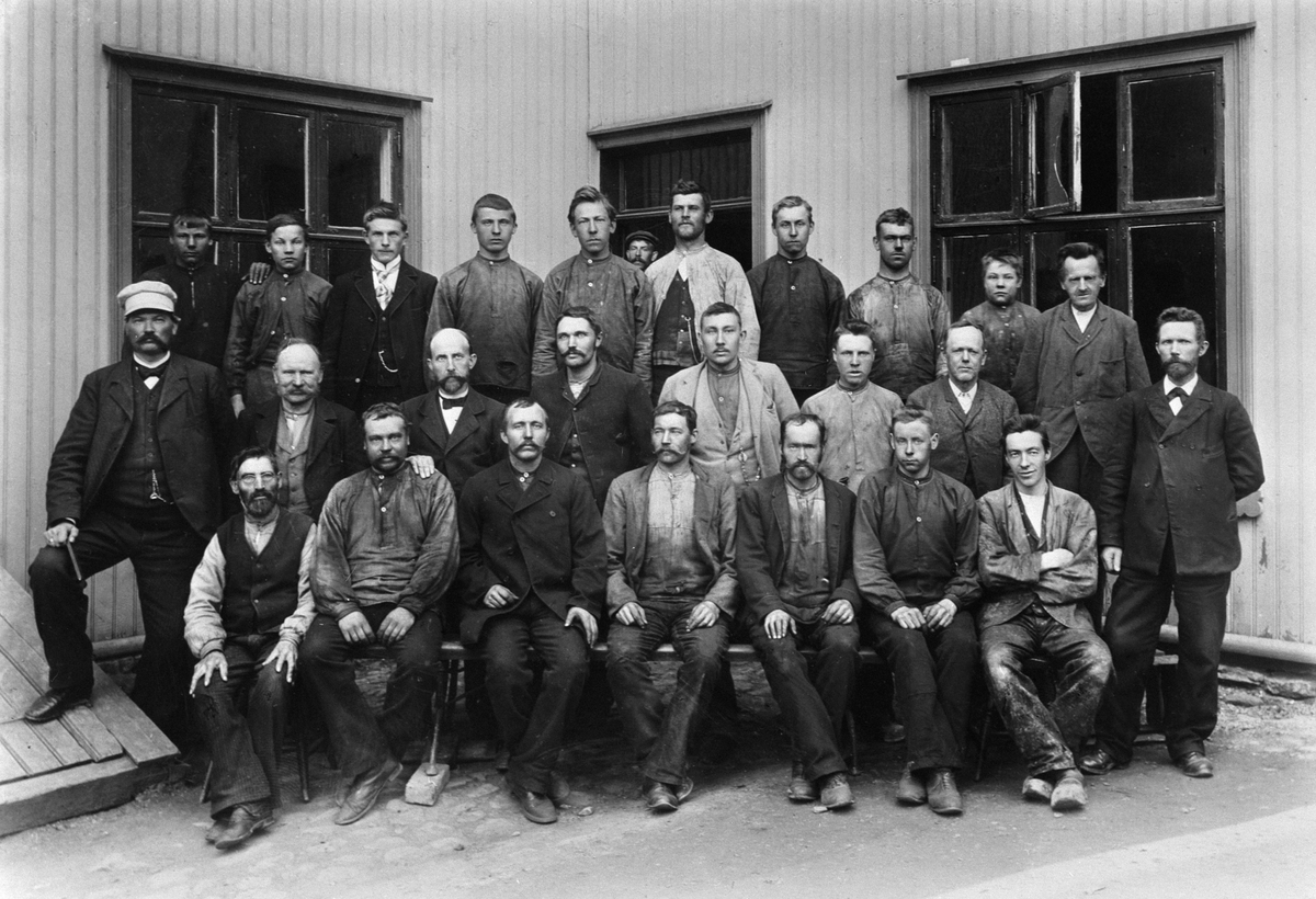 Anno Domkirkeodden, Gruppe 25 arbeidere, Lunds Vognfabrikk i Hamar, håndverkere. T. v. Andreas Lund med skyggelue, mannen midt i bildet med lys dress og klokkelenke er Ole Peder Holter.