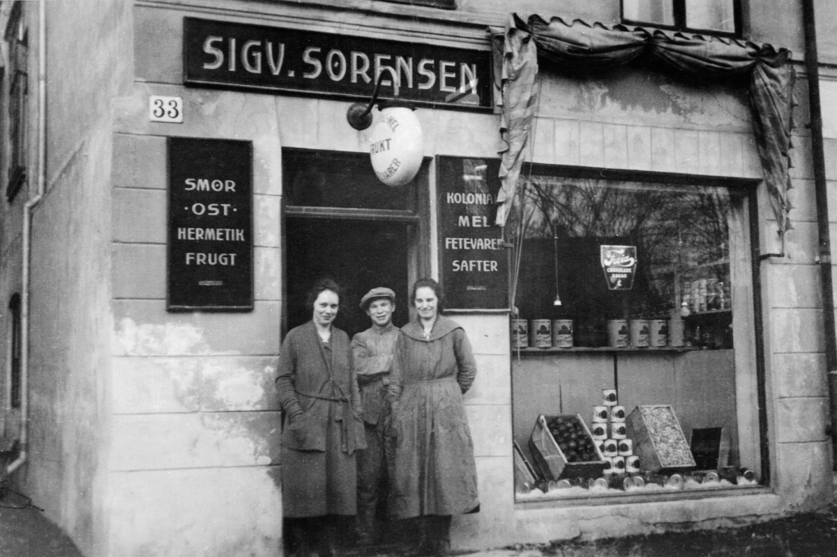 Anno Domkirkeodden, GRUPPE 3, BUTIKKPERSONALET, SIGV. SØRENSEN, G. JAKOBSEN, O. BIRKELANDPå bildet: Gønner Jakobsen, visergutt Harald Syversen, Ovidia Birkeland, Ekspeditrisene arbeidet tilsammen hosSigv. Sørensen i 103 år.