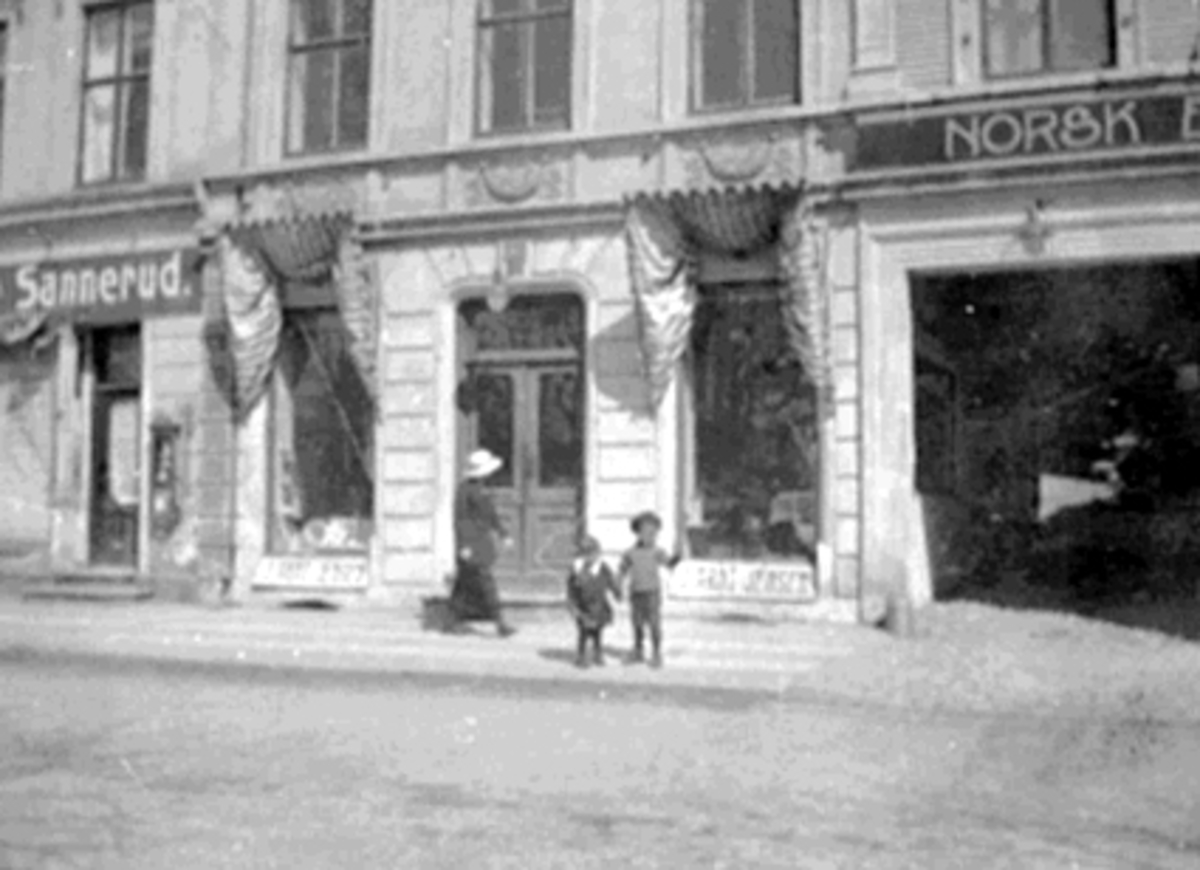Anno Domkirkeodden, Strandgata 53, Hamar. Inger Margrethe Jensen og Gulbrand "Gubbe" Jensen utenfor farens forretning. J. Arnt Jensen EKSTERIØR STRANDGT. 53, SANNERUD, J. ARNT JENSEN,