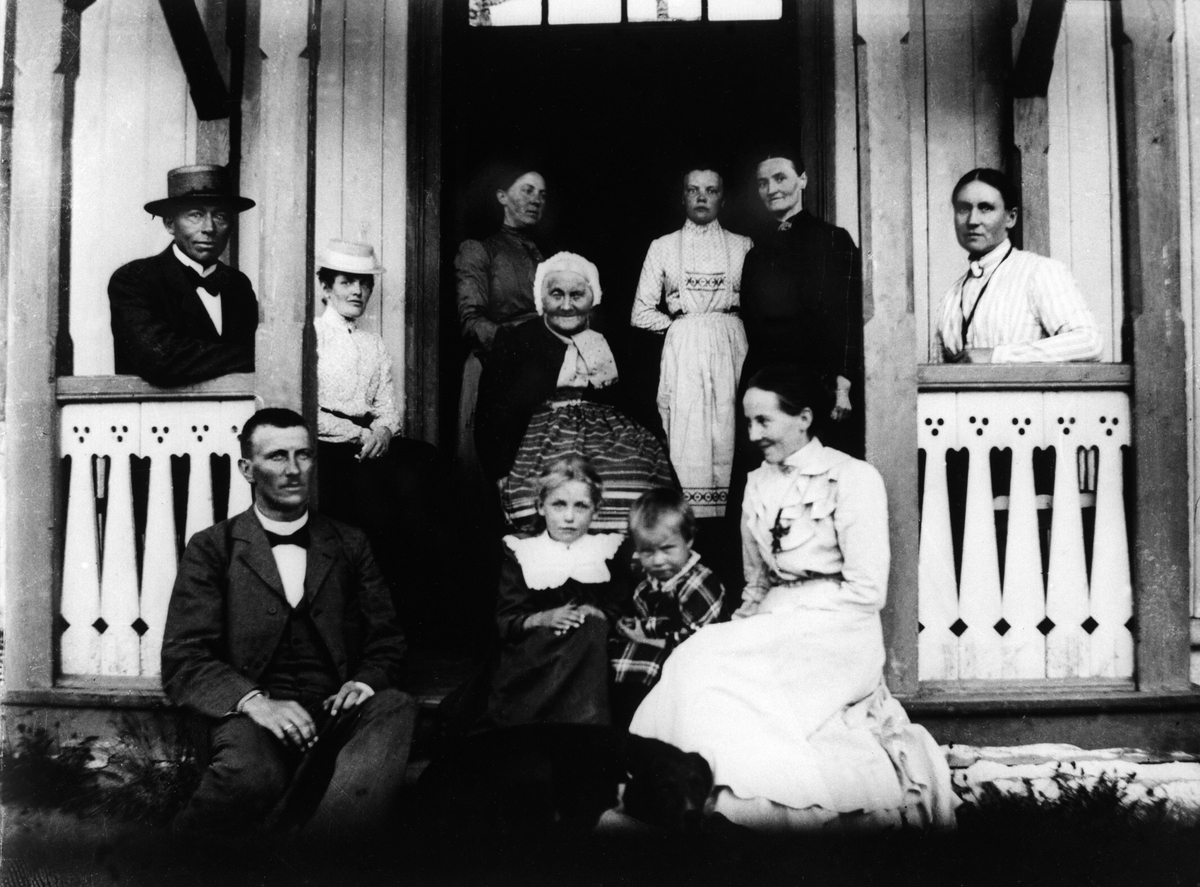 Anno Domkirkeodden, Disen, vestre gård, veranda. 1. rekke f.v. Eivind Harder f. 1869,, ukjent, Fridtjof Harder f. 1901, Valborg Harder f. 1879. Mann med hatt, Karl Andreas Diesen, kvinne med hatt Karoline Diesen. I midten Karine Torshaug. De øvrige ukjente.