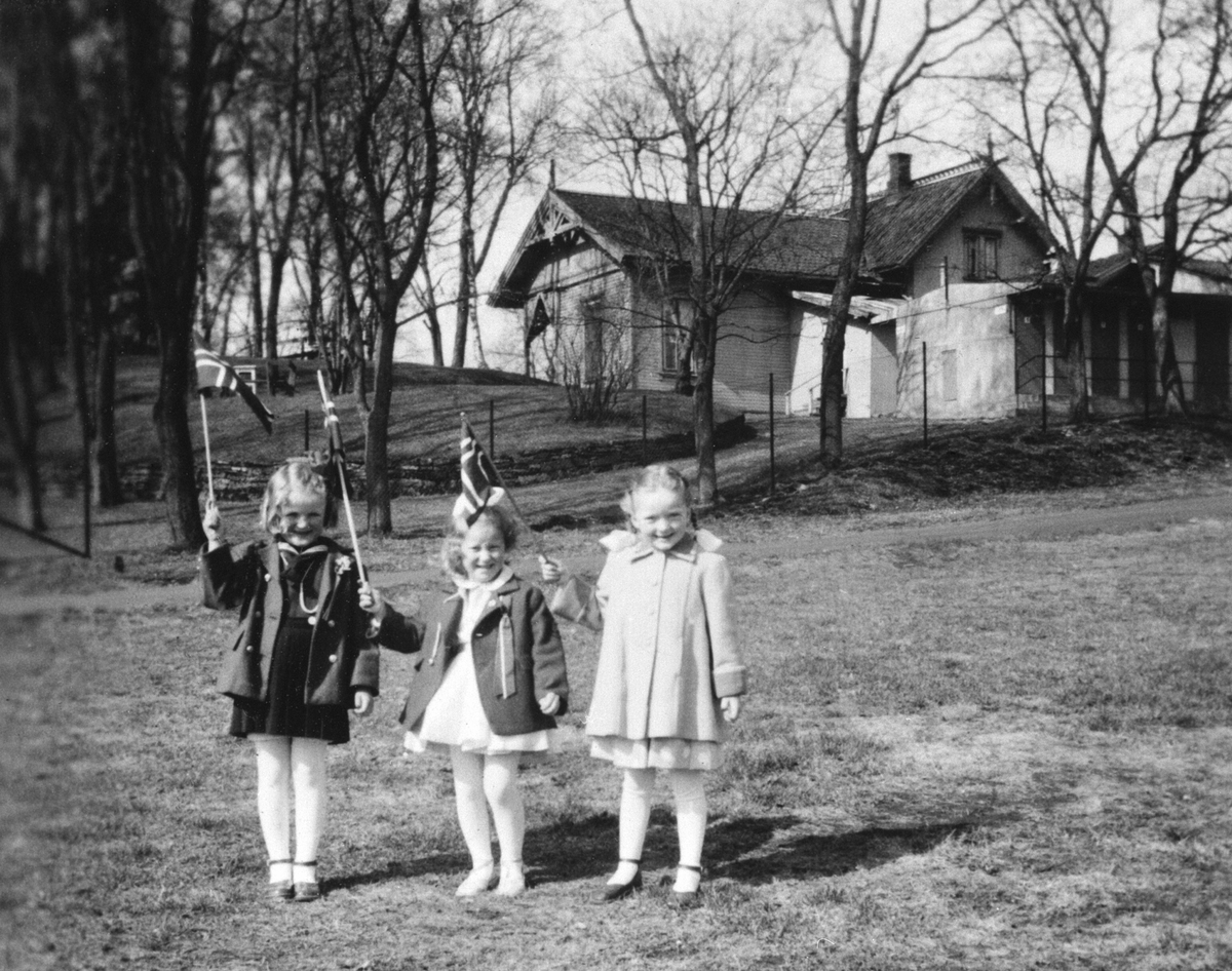 Anno Domkirkeodden, BARN. 17. MAI. FLAGG. FRA VENSTRE SOLVÅR RYNNING, MAI SUTTENBERG, KARI JENNY BINGEN. VAKTMESTERBOLIGEN OG TOALETTBYGGET I HAMAR PARK I BAKGRUNNEN.