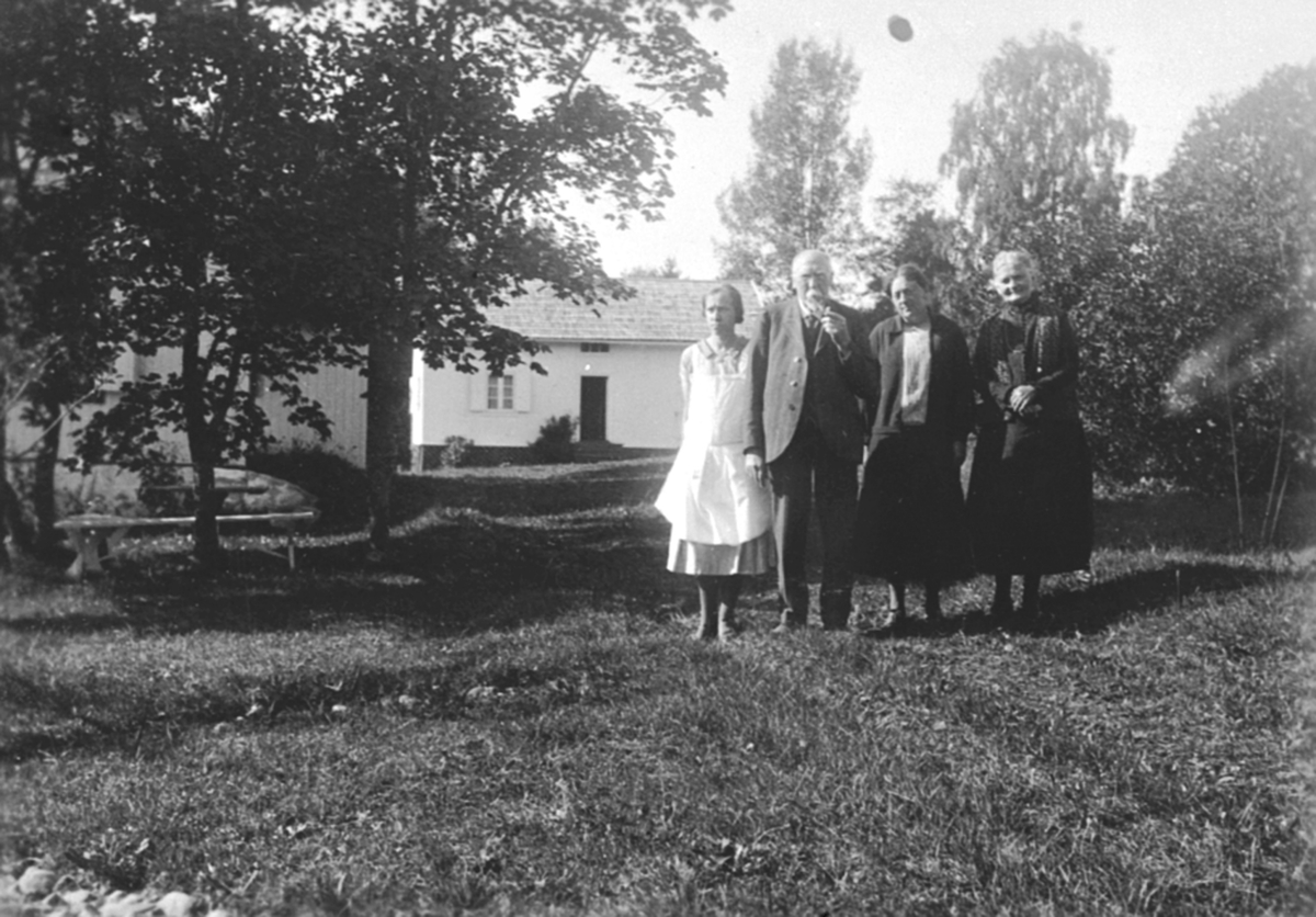 Anno Domkirkeodden, Gruppe: 4, familien Johan Nordhagen, Veldre i Ringsaker. Grafikeren Johan Nordhagen (nr 2 fra v. ) med hustru Christine (nr 4) og hjemeværende døtre (lærerinner) Marie (nr 1) og Aslaug (også kunstnerinne, nr 3) foran bruket Fjeldberg på Veldre, som de leide hver sommer. Christine døde i 1933 så bil…