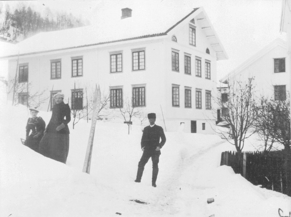 Anno Domkirkeodden, To kvinner og en mann foran tjenerboligen på Berg gård, Brøttum, Ringsaker. Utleid i forbindelse med jernbaneutbyggingen.