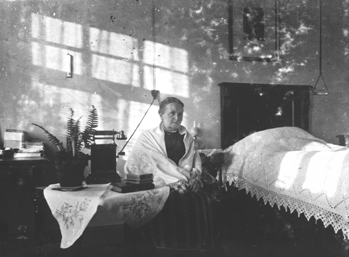 Anno Domkirkeodden, Interiør, soverom. Lisbeth Grüner (1847-1918) ved senga. Telefon på bord. Granerud gård, Brumunddal.