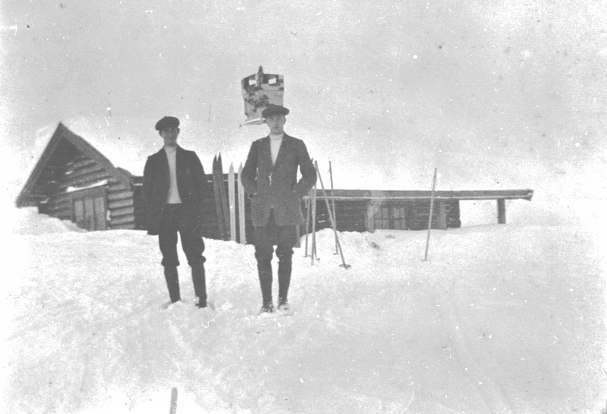 Anno Domkirkeodden, To menn med ski utenfor hytte. Familien Løken, påskeferie, fritid.