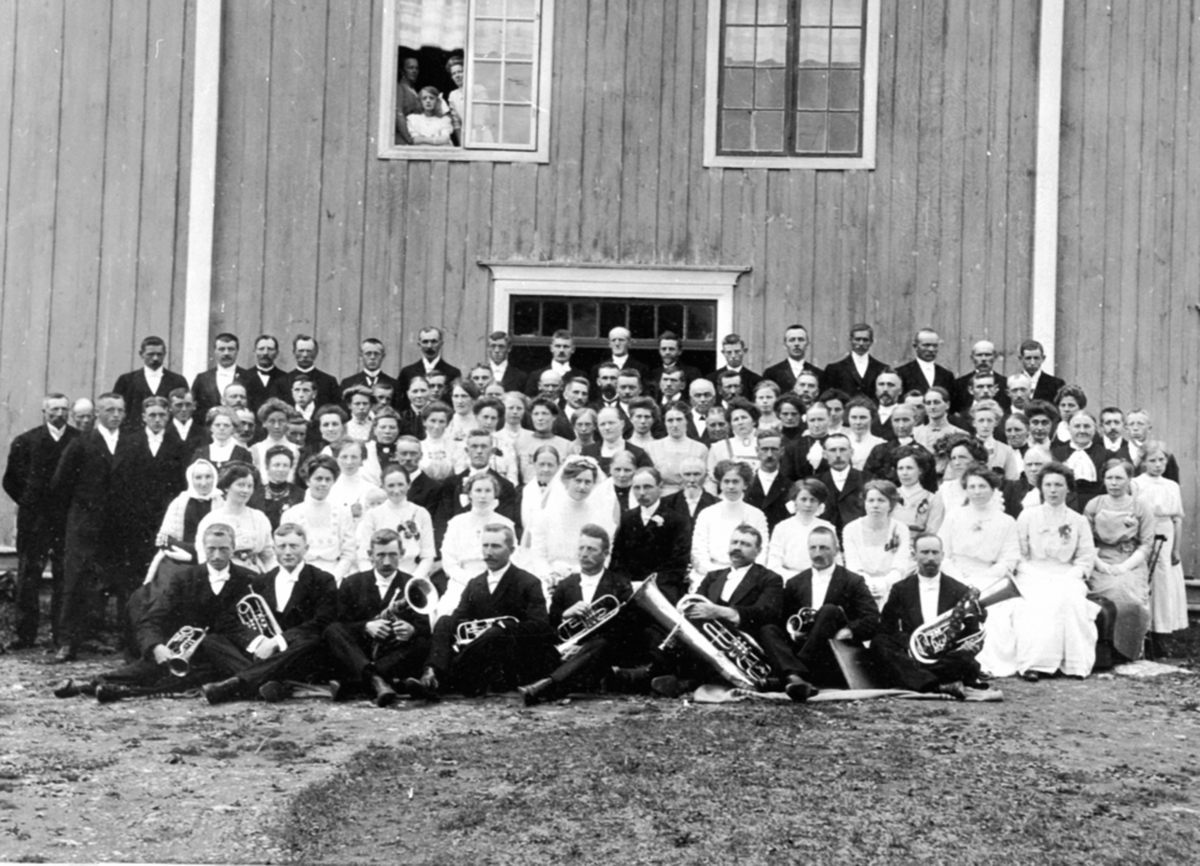 Anno Domkirkeodden, Stor gruppe bryllupsgjester og brudepar på Lund nordre, Furnes. Musikere med instrumenter i forgrunn.