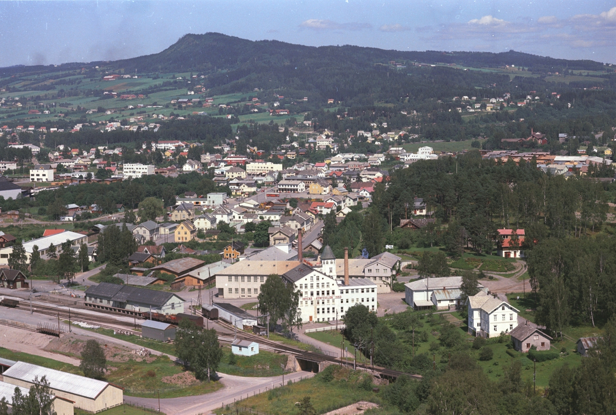 Widerøes Flyveselskap A/S, Flyfoto, Brumunddal. Høyens konfeksjonsfabrikk, potetmjølfabrikken og jernbanen i forgrunnen.