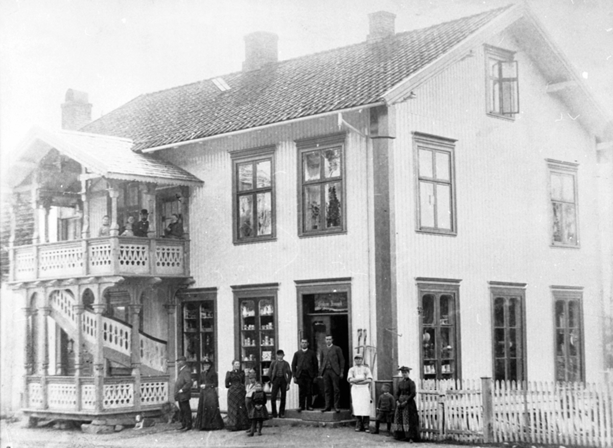 Anno Domkirkeodden, Eksteriør, Øverenga, brødrene Jevanord landhandel, etter 1917, Thingelstadgården, fra venstre er Hans Jevanord, Oline Jevanord, Karen Jevanord (goft Kristiansen), 2 barn, Petter Olai Jevanord, baker Sandberg. På veranda er Johannes og Gina Jevanord, ukjente batn. Gamlegata, Brumunddal.