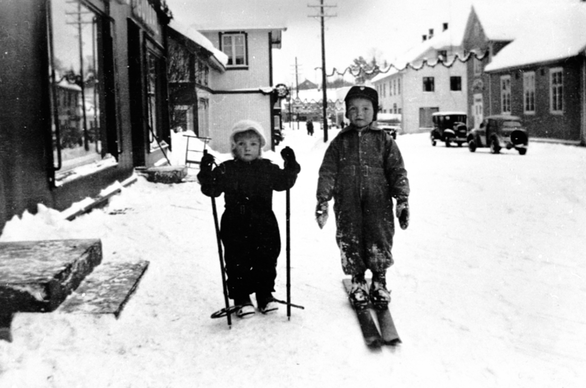 Anno Domkirkeodden, 2 barn med ski og staver i Furnesvegen, Brumunddal. Pyntet julegate.