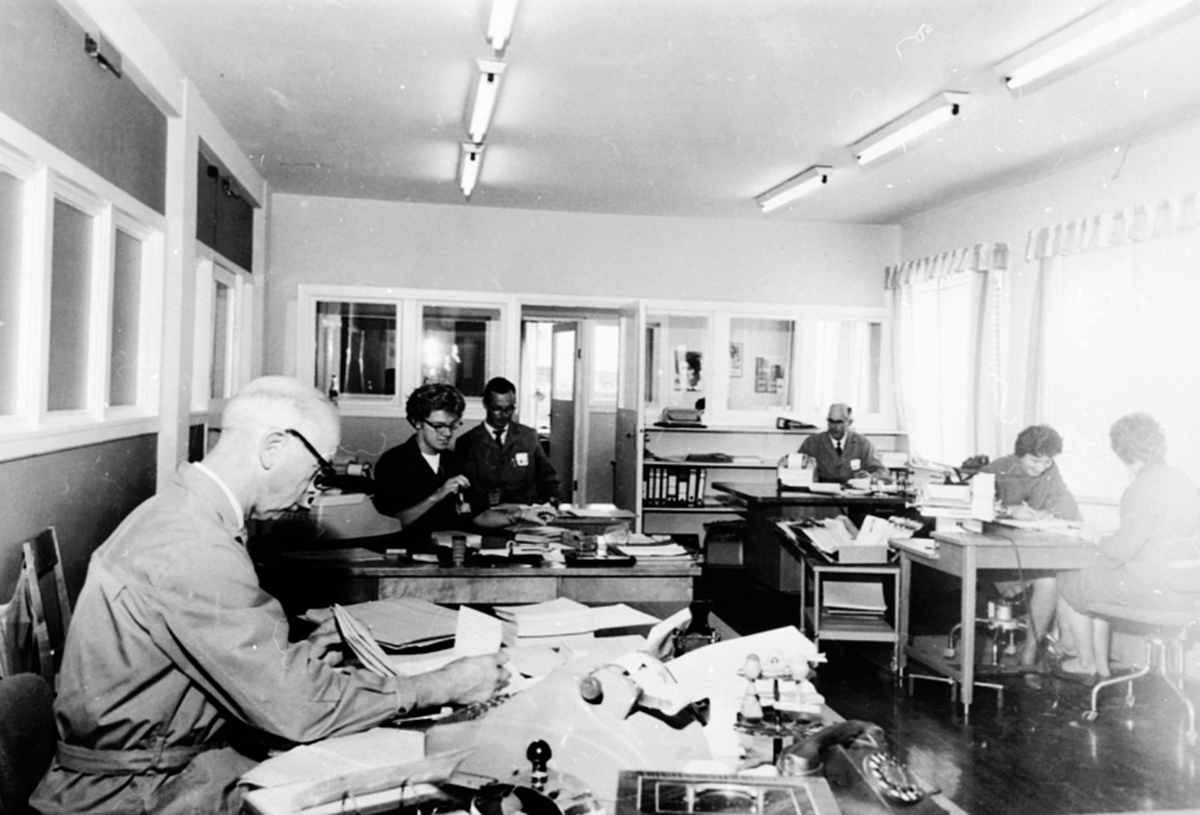 Anno Domkirkeodden, Interiør, kontoret på A/S Oplandske Konservesfabrikk, Stabburet, Nora, Brumunddal. Fra venstre er Johan Lindback, Astrid Bjerke, Harald Strand, Hans Nordsveen, Magnhild Skår (gift Børresen), Anne Lise Pram (gift Christensen).