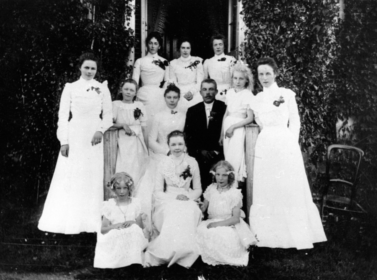 Anno Domkirkeodden, Bryllup, Granerud gård, Brumunddal. Martha og Axel Dobloug. Foran fra venstre er Hjørdis Løken gift Helsingen, Houmb gift Solli, Marie Løken gift Arisholm. Andre rekke fra venstre er Berthe Narud gift Dobloug, ukjent, brudeparet, Erika Doblug gift Lien, Agnes Østby. Bak fra venstre er Amundsen gift…