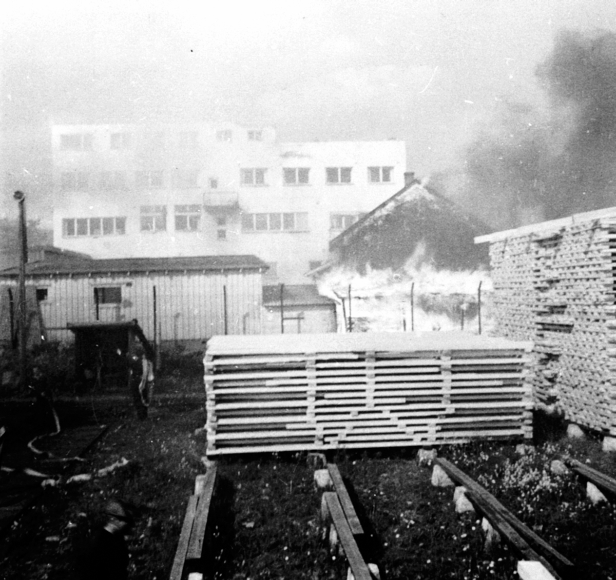 Anno Domkirkeodden, Storbrann ved Berger Langmoen AS, Brumunddal. Hus brenner, frivillige hjelper til med slokningsarbeidet. Materiallager i forgrunn.