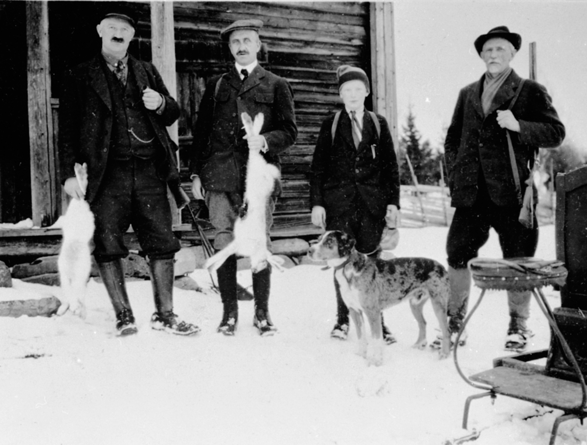 Anno Domkirkeodden, Gruppe jegere med gevær og hund, harejakt, Ødegården, sommerseter ved Opsal, Veldre, Ringsaker. Fra venstre er Anders Opsal, Olav Jørstad, Jørgen Opsal, Einar Narud.