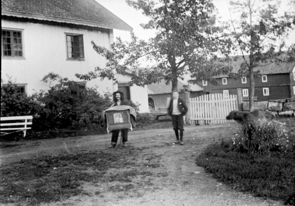 Anno Domkirkeodden, Omvandrende lirekassemann på gardstunet på Ulven gård, Ringsaker. Hans Ulven hører på.