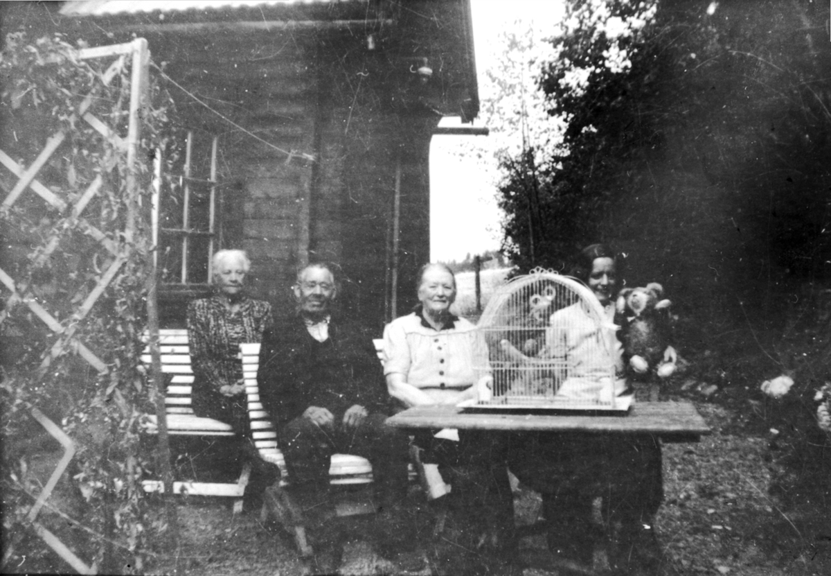 Anno Domkirkeodden, Sund Nedre, Helgøya. Familiegruppe Randby. Fra venstre er Hanna, Gustav Randby (1869-1952), Grete Marie (1873-1960) og Helene (1914-1968). Hanna var vaktmester Gustav Randby sin søster. Papegøye i bur. Teddybjørn.