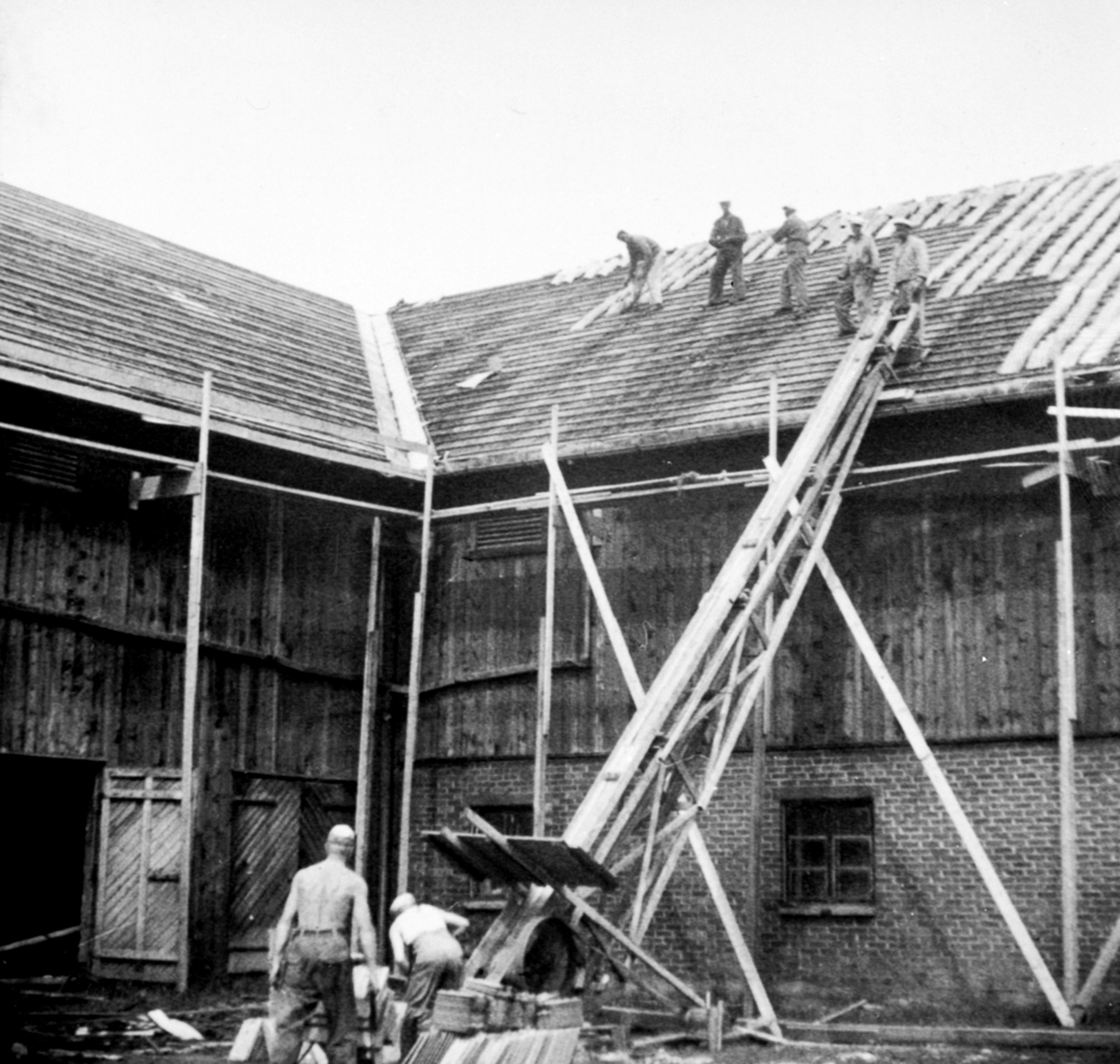 Anno Domkirkeodden, Legging av takstein på låvetaket på Heggenhaugen, Ringsaker. August Østvold med arbeidere. Andr. Heggenhaugen ved heisen, Aksel Snuggerud med trillebår.