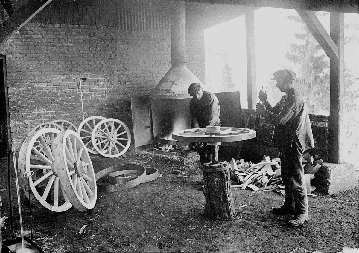 Anno Domkirkeodden, Interiør fra smia, også kalt for "Helvete". Trehjulene beslås med en jernring. Smed Anton Kamperud og smedgutt Ole Øverli ignag med trehjulsproduksjon på Moelven Brug, Ringsaker.