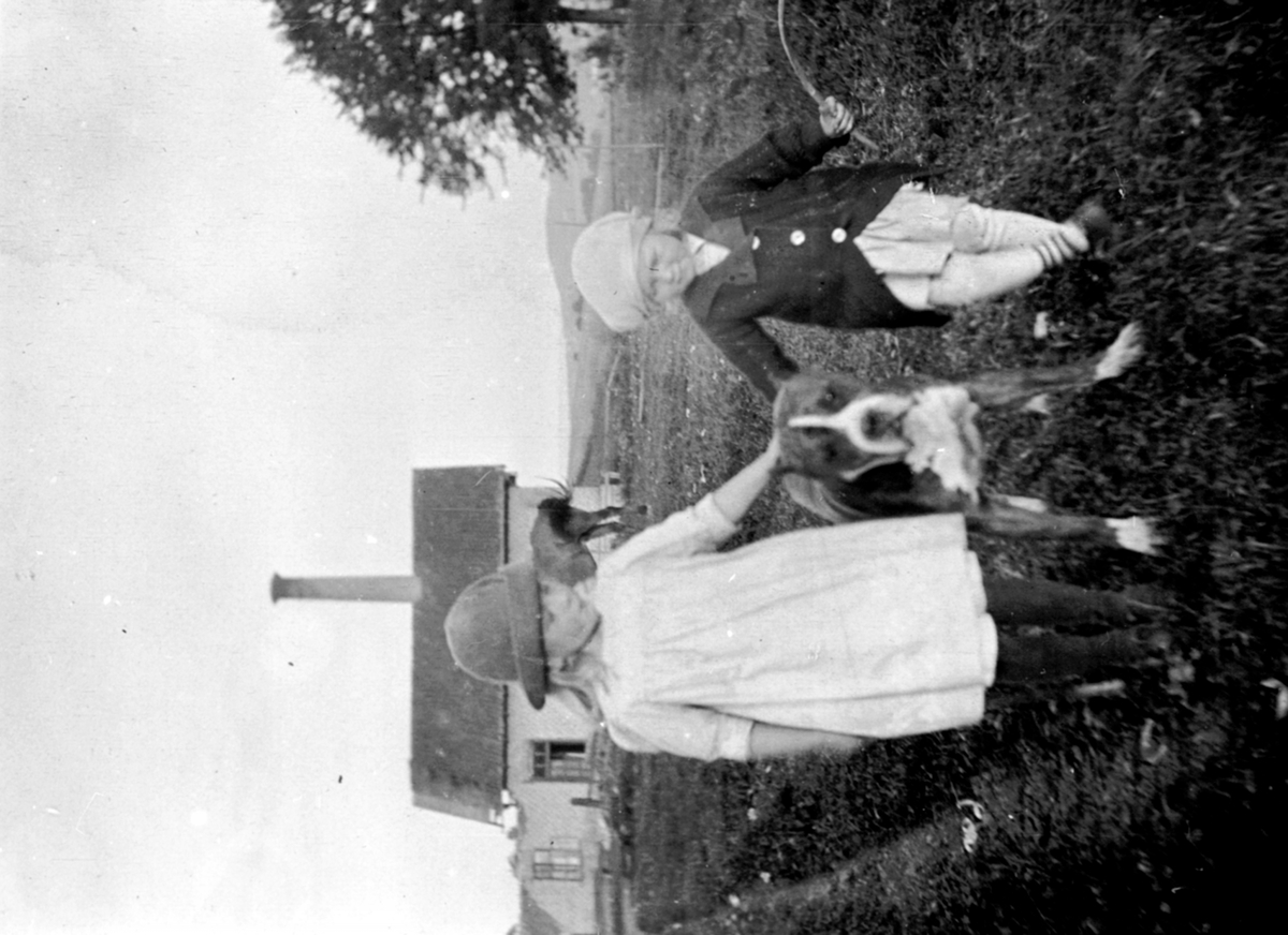 Anno Domkirkeodden, To jenter med hund på Hoel gård, Nes, Hedmark. Margrethe Louise (Babs) Kildal. I bakgrunnen det gamle meieriet som rives og ominnredes som herskapsstall.