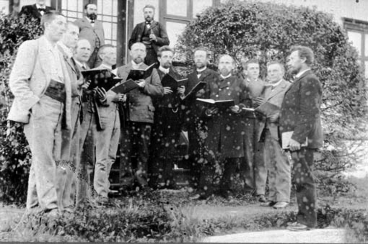 Anno Domkirkeodden, Ringsaker mannskor. Fra venstre er Mikkel Sveinhaug, Johannes Smedstad, Klaudi Solberg, Even Bye, Helmer Solberg, Hans Skappel, Petter Syverud, Christian Røhne, Jørgen Dæhli, Chr. Fjelstad, dirigent Torstein Kolsgaard. På veranda er Johannes Sundgaard, Anton Fjelstad og Peder Hjelt, Fjølstad østre,…