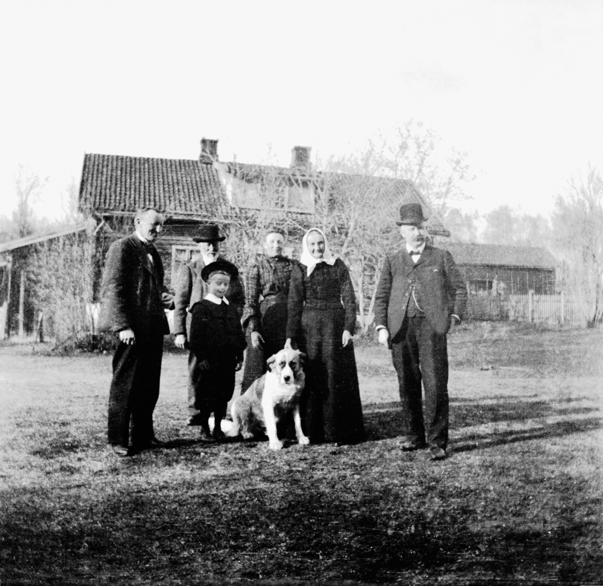Anno Domkirkeodden, Føderådsbygningen på Helgeby, Nes, Hedmark. Voksne barn og hund. Fra venstre er Karl Helgeby , Jacob Olsen Lie (1832-1918), Syverine Helgeby f.1866, Juline Lie Helgeby, Ole Helgeby, Ester?. Føderådsbygningen bygd 1870.