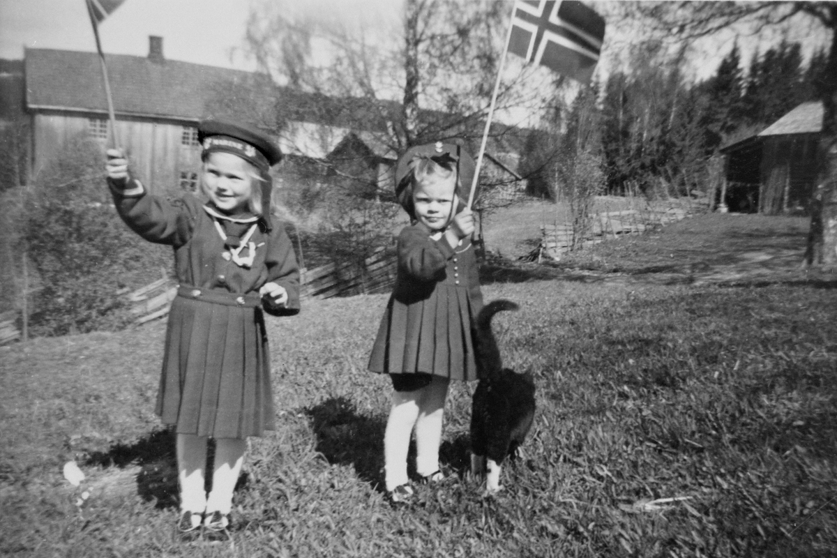 Anno Domkirkeodden, 2 jenter med flagg og matroskjole, 17. mai. I bakgrunnen Gjerlaugbakken og Engelstad. May Gislaug Godager og Laila Oliv Godager.