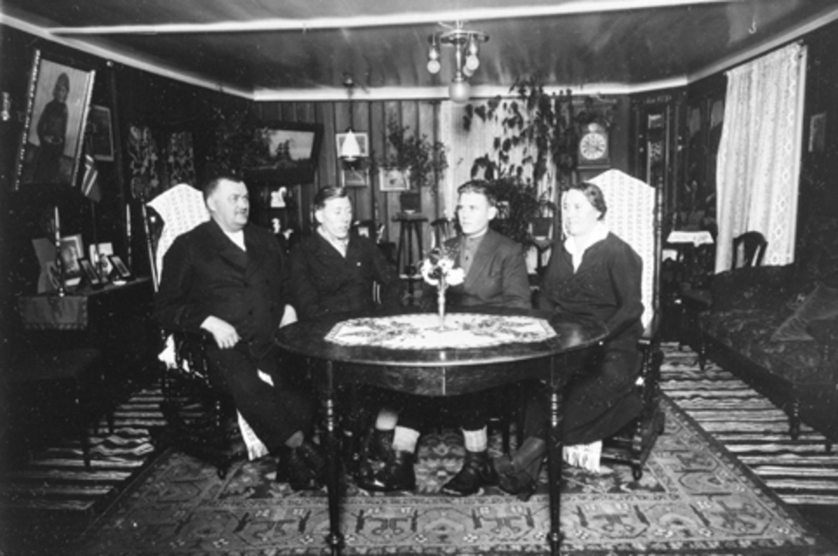 Anno Domkirkeodden, Interiør, stue, Jesnes øvre, Furnes, Ringsaker. Familien Haave/Jesnes rundt salongbordet. Fra venstre er Bernt Haave F:1884, Gudbrand Haave F: 1914, Andreas Jesnas F: 1910, Kari Haave F: 1884.