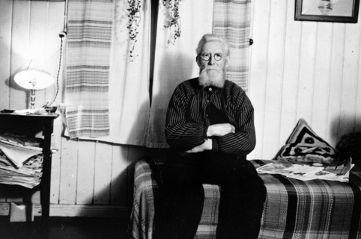 Anno Domkirkeodden, Interiør, oppholdsrom, divan, bord med lesestoff, Anders Haugli på senga. Ringsaker.