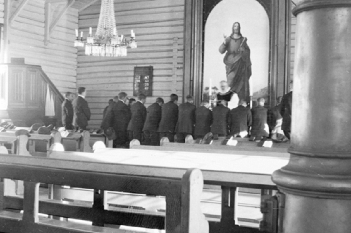 Anno Domkirkeodden, Interiør i Helgøya kirke. Gutter fra Toftes Gave kneler ved alteret foran den gamle altertavlen.