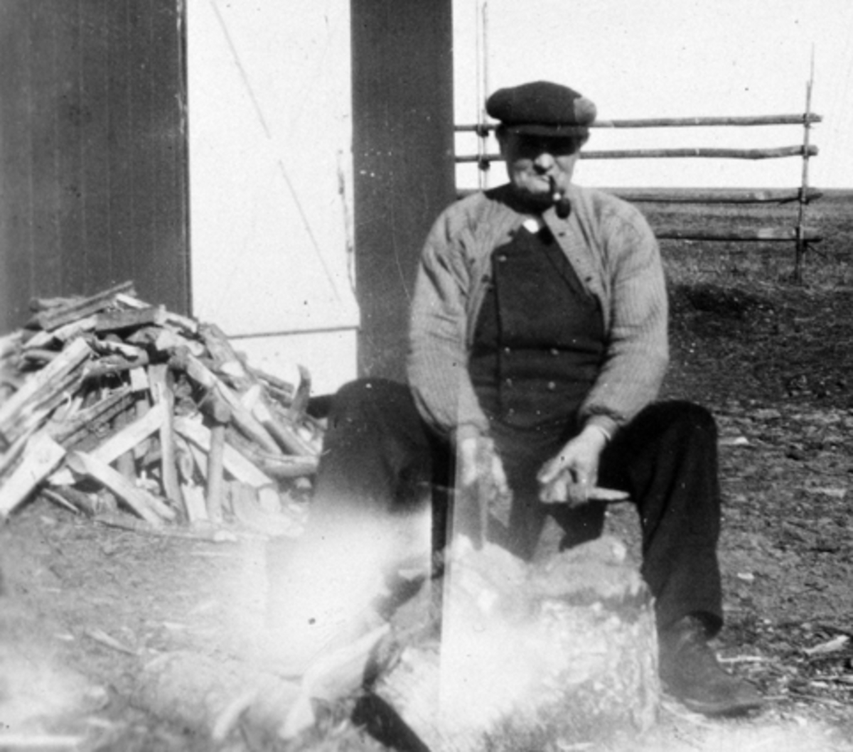 Anno Domkirkeodden, Eldre mann med pipe kløyver ved på Tveiter, Stavsjø, Hedmark.