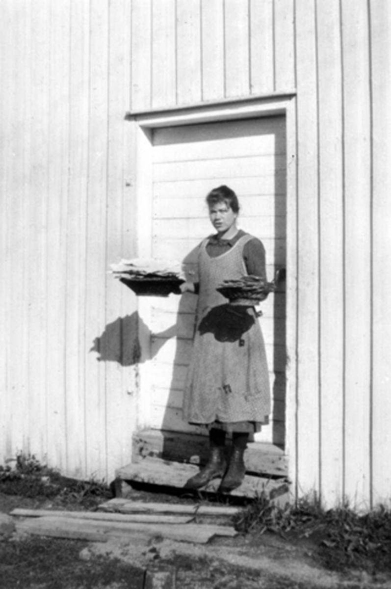 Anno Domkirkeodden, Emma Jevanolbakken henter flatbrød på stabburet på Mørkved store, Ringsaker. 1920.