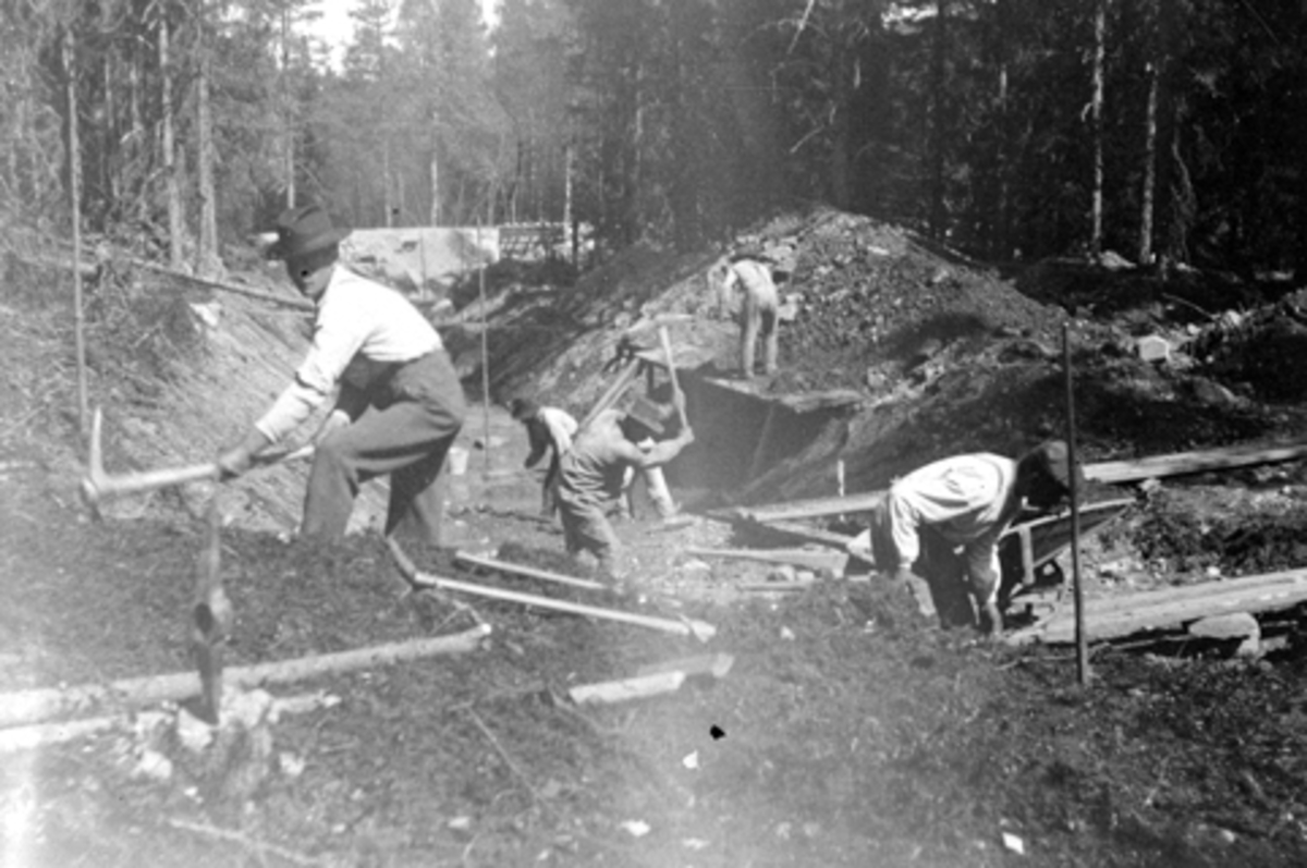 Anno Domkirkeodden, Utgraving av tilførselkanal til Moelv kraftstasjon, ble bygget for Moelv Cellulosefabrikk ca. 1907-1909. Kanalen var 1600 meter lang og kraftverket produserte ca. 800kw. Arbeidere med hakke, spade og trillebår.
