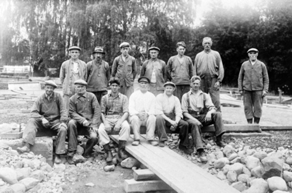Anno Domkirkeodden, Arbeidere bygger lagerskur på Strand Brænderi i 1939. Foran fra venstre er Johannes Solberg, Valdemar Johansen, Paul Eng, Anton Syverstuen, Karl Evensen, Ingvald Grøndal. Bek fra venstre er Johannes Olafsen, Even Oddvik, Kåre Johansen, Albert Smikkerud, Thorvald Nysveen, Peder Fredheim, Johan Stens…