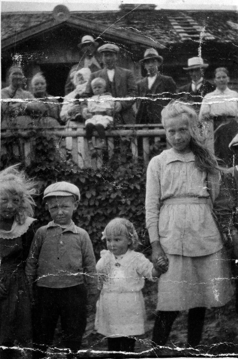 Anno Domkirkeodden, Gruppe personer på Skaugen østre, Veldre, Ringsaker, ca. 1920. Foran fra venstre er Anna Skaugen, Arne Haugli, Bertha Skaugen, Marie Skaugen, Paul Skaugen. Bak fra venstre er Sissel Skaugen, Pernille Skaugen, Karen og Lars Haugli med hvert sitt barn, bak dem er Johs Skaugen, Svein Skaugen, Petter S…