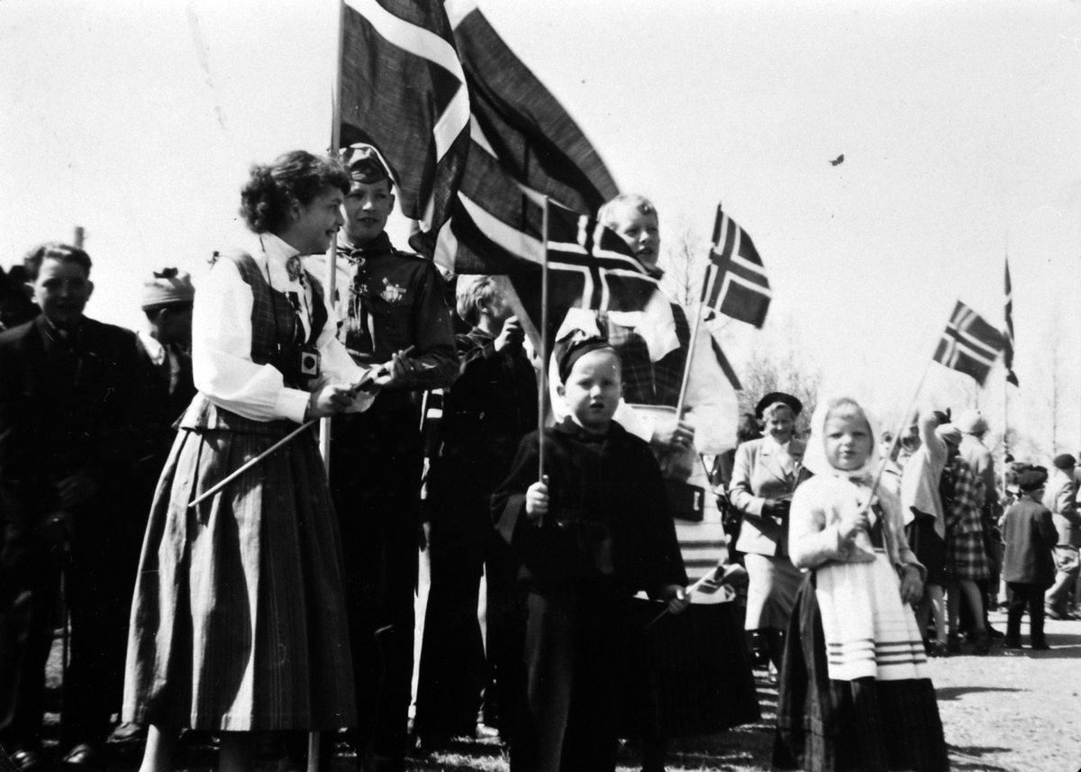 Anno Domkirkeodden, 17. mai på Furu skole, Veldre, Ringsaker. Festkledde mennesker i bunad, barn med flagg. Piken i bunad er Karen Ellen Østby, flaggbærer er Jacob Rud