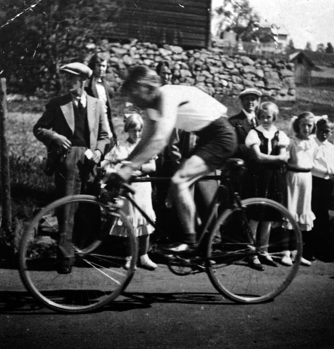 Anno Domkirkeodden, Karstein Rustad på sykkel, han syklet for Veldre AIL i perioden 1936-40, aktiv både på sykkel og ski. Tilskuere bak.