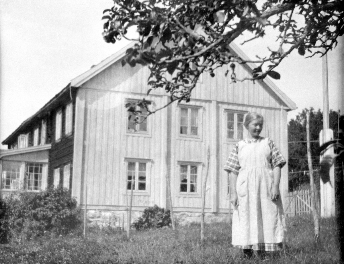 Anno Domkirkeodden, Eksteriør. Hovedbygningen på Sterud nordre, Nes, Hedmark. Inga Nygaard født Moen (1894-1964) står ved flaggstanga.