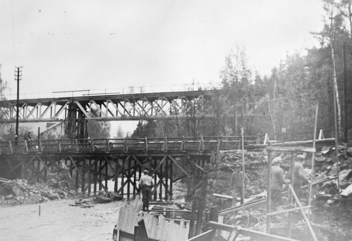 Ukjent, Jernbanebrua over Moelva. Gjenoppbygging og reparasjon etter sprengningen 19. april 1940. Jernbanebrua har understøttelse av tre før den solide gråsteinspilaren er gjjenoppmurt. 2. verdenskrig.