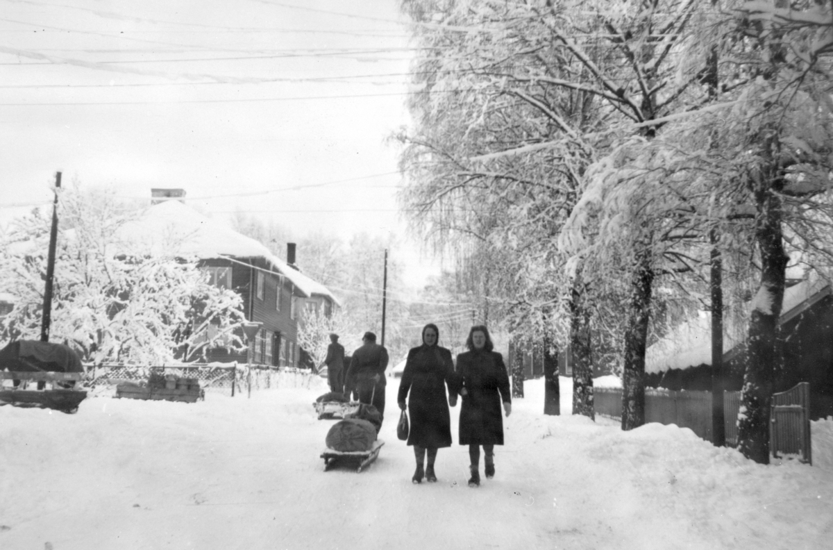 Ukjent, Moelv sentrum, to menn drar kjelke med varer. To ukjente kvinner, vinter.