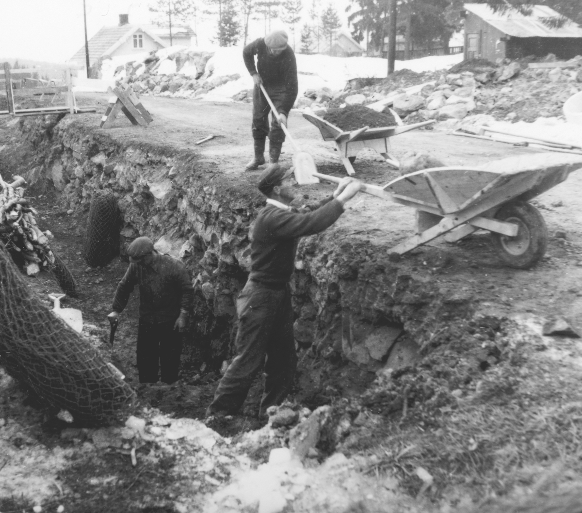Ukjent, Pinnerudvegen i Moelv. Graving og legging av ny vann og kloakkledning ca. 1952-1955. Graving for hånd, trillebår, spader. Grøft.