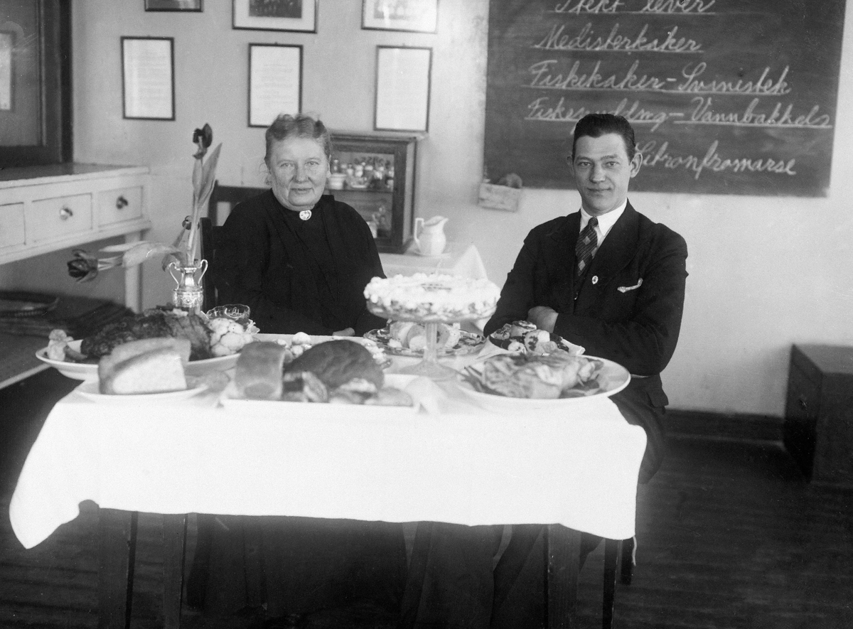 Anno Domkirkeodden, HENRIETTE SCHØNBERG ERKEN OG BESTYRER JOHN HANNEVIG OLSEN (TØNSBERG). MATBORD. TEKST PÅ KARTONG "HILSEN TIL FRU SCHØNBERG ERKEN FRA BESTYRER JOHN HANNEVIG OLSEN, TØNSBERG"