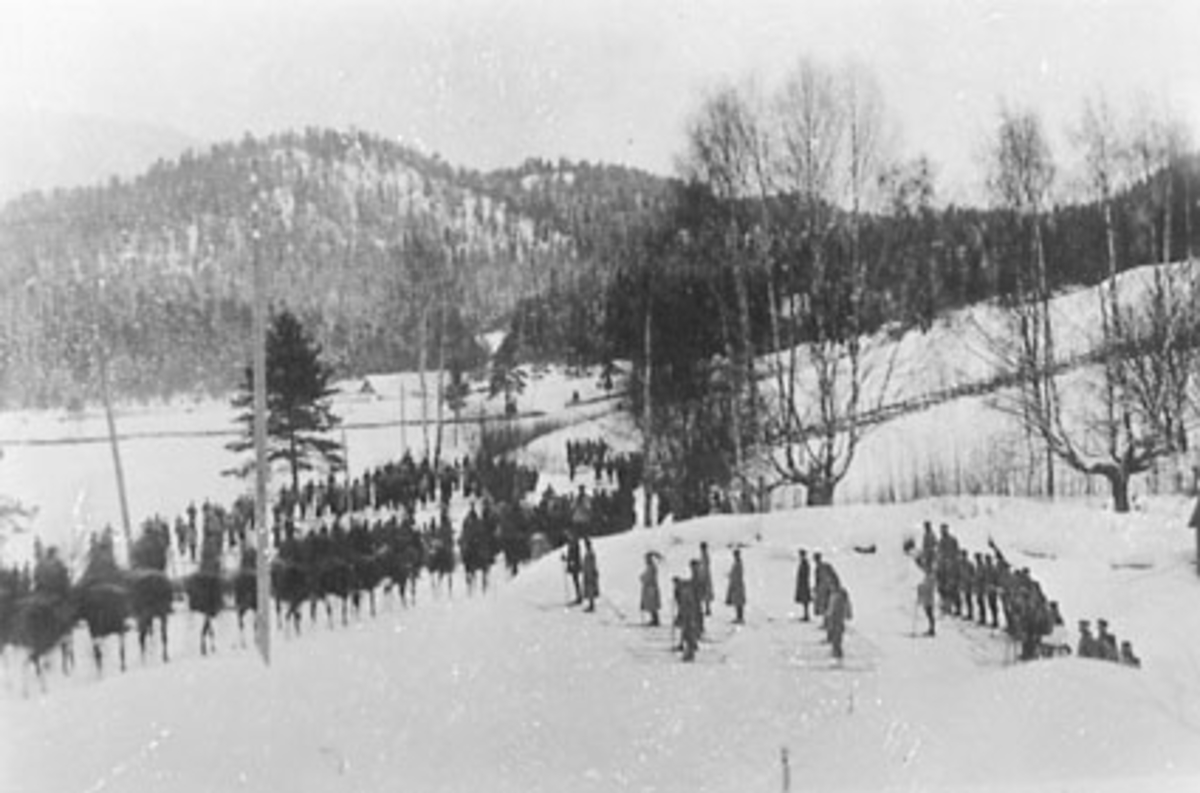 Anno Domkirkeodden, FELTMANØVER, JØNSRUD, H. K. H. KONG HAAKON VII, KRONPRINS OLAV, GENERALSTABEN, MILITÆR VINTERØVELSE. Fra vinterøvelsen på Tangen i 1937. Oppstilling for kongen, kronprinsen og Hærens ledelse på den andre sida av vegen for Jønsrud. Langs vegen står elevene fra tangen skole med blant annet Odvar Nord…